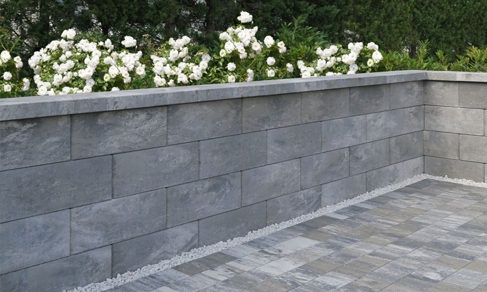 Štandardná plotová a múrová tvárnica, kamenná sivá tieňovaná; Krycia platňa s odkvapovým nosom 25 x 28 x 6 cm, kamenná sivá tieňovaná a Capris dlažba, kamenná sivá tieňovaná