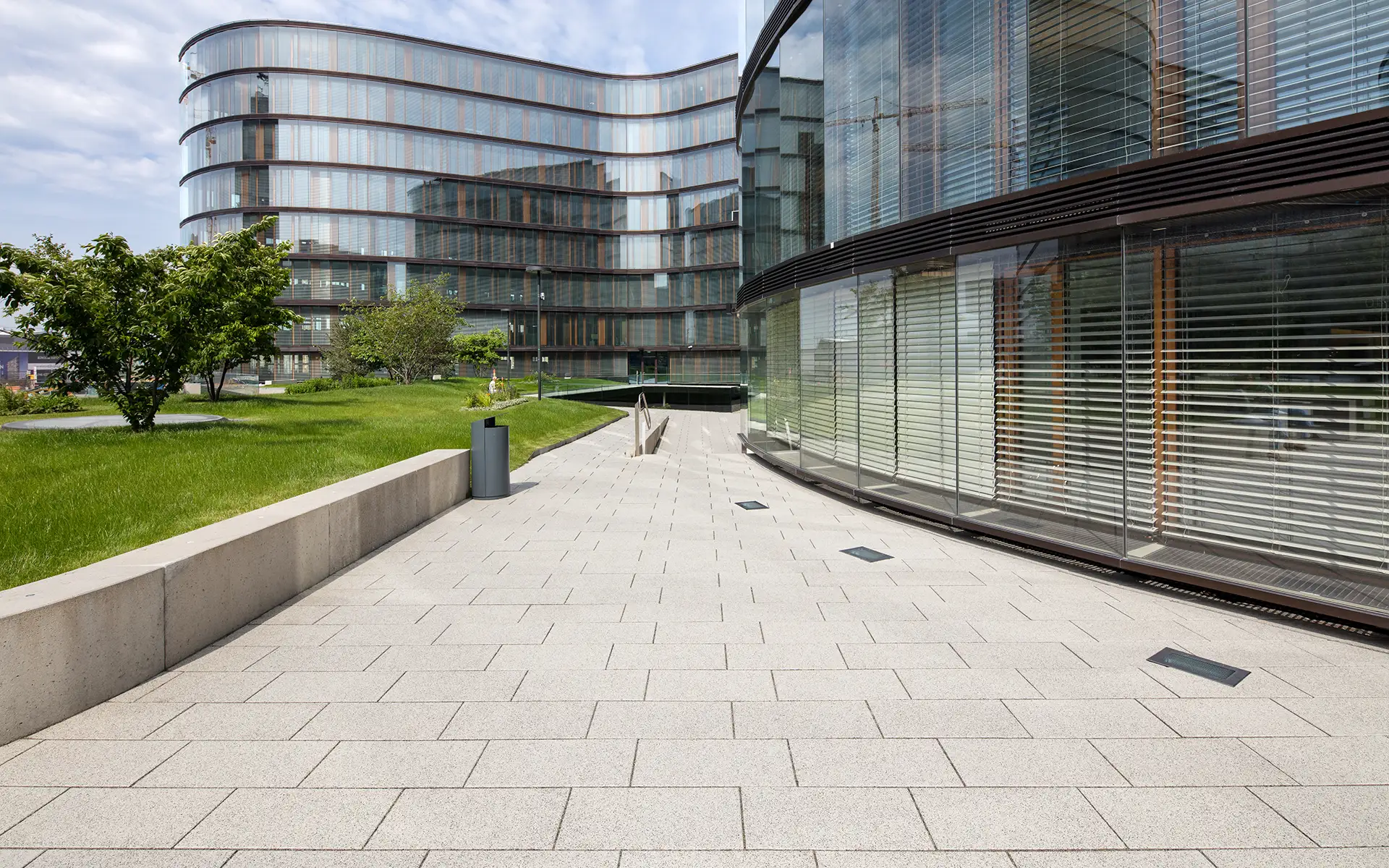 Chodník pri zelenej ploche s Largo podlahovou platňou bielo-čierne kamenivo pri Erste Group/Erste Campus Friedl Steinwerke.