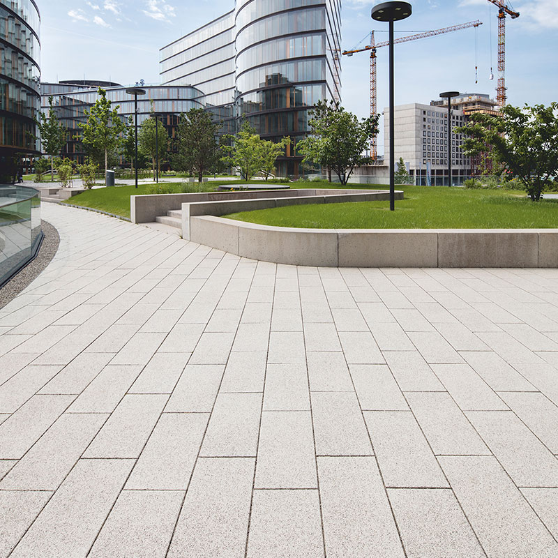 Chodník pri zelenej ploche s Largo podlahovou platňou bielo-čierne kamenivo pri Erste Group/Erste Campus Friedl Steinwerke.