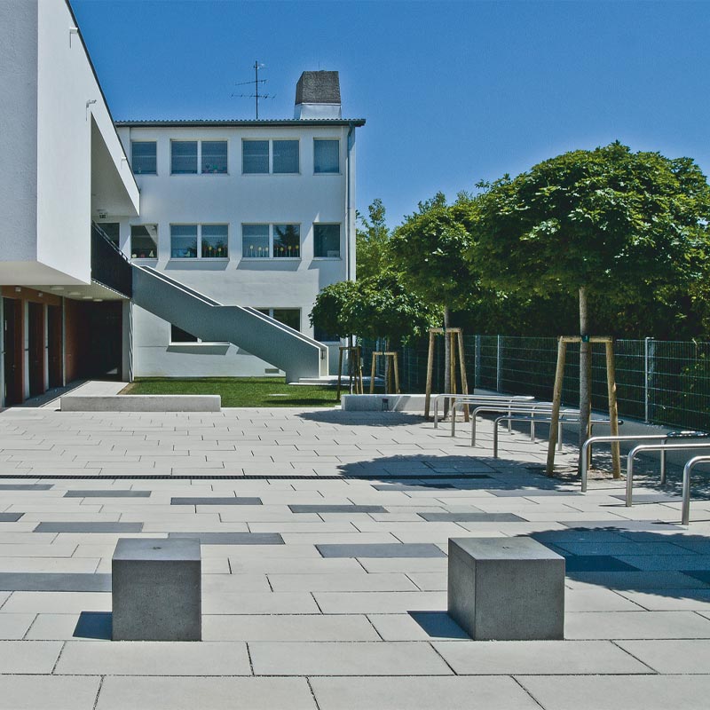 Volkschule Wiener Neudorf Magnum, sivá-antracitová betónové dlažby Friedl Steinwerke Volkschule Wiener Neudorf Magnum, sivá-antracitová betónové dlažby Friedl Steinwerke