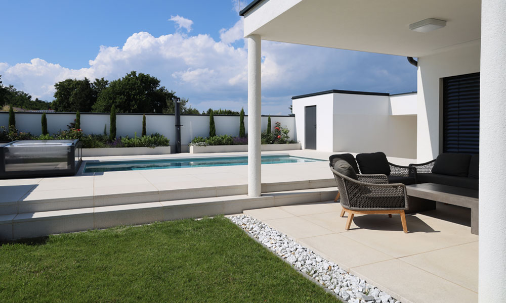LIV kremencová od Friedl Steinwerke ako terasová dlažba okolo bazéna a v krytom lounge priestore – moderný záhradný dizajn s čistými líniami. LIV kremencová od Friedl Steinwerke ako terasová dlažba okolo bazéna a v krytom lounge priestore – moderný záhradný dizajn s čistými líniami.
